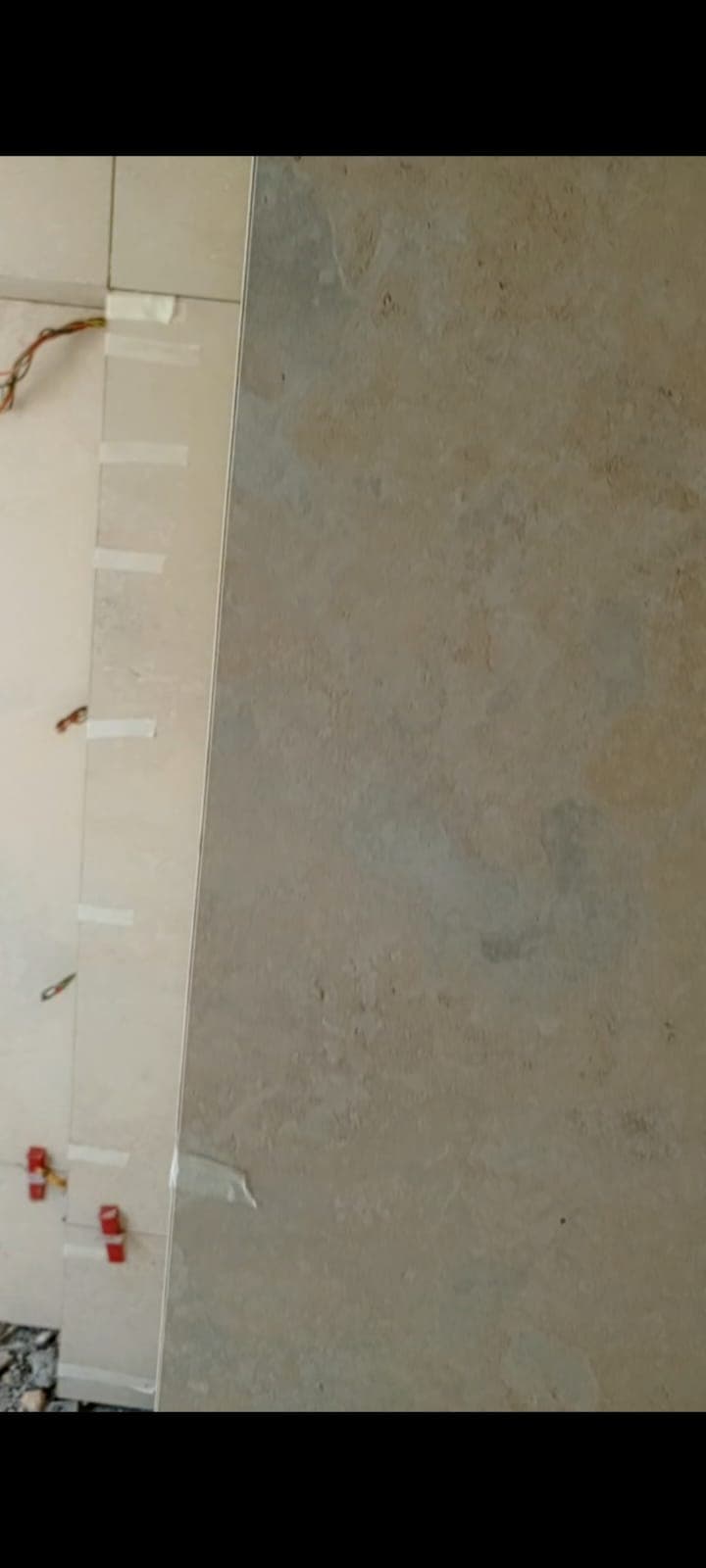 Internal corner of the bathroom with large cream porcelain tiles aligned and taped, Askari 10 Islamabad