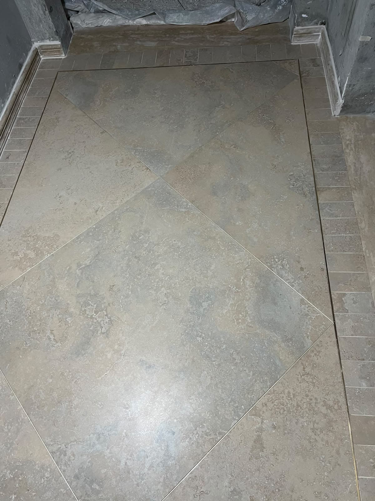 Symmetrical corridor layout with diamond-laid porcelain tiles, brass accent trim, and stacked border tiles in Askari 10