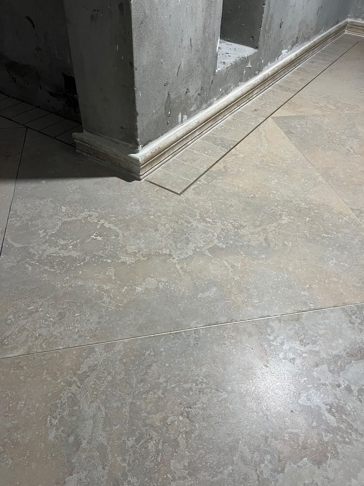 Corner pillar base with mitred stone skirting moulding, rectangular border tile, and diagonal porcelain floor tile in Askari 10 residence, Islamabad