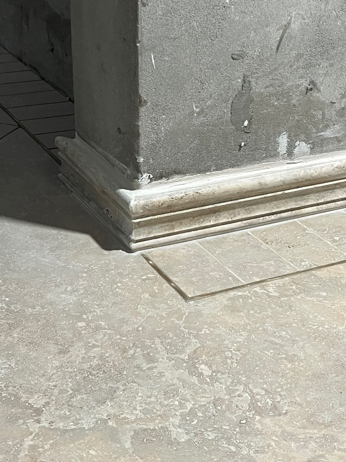 Close-up of precision hand-mitred classical stone skirting moulding around a structural pillar base in Askari 10, Islamabad