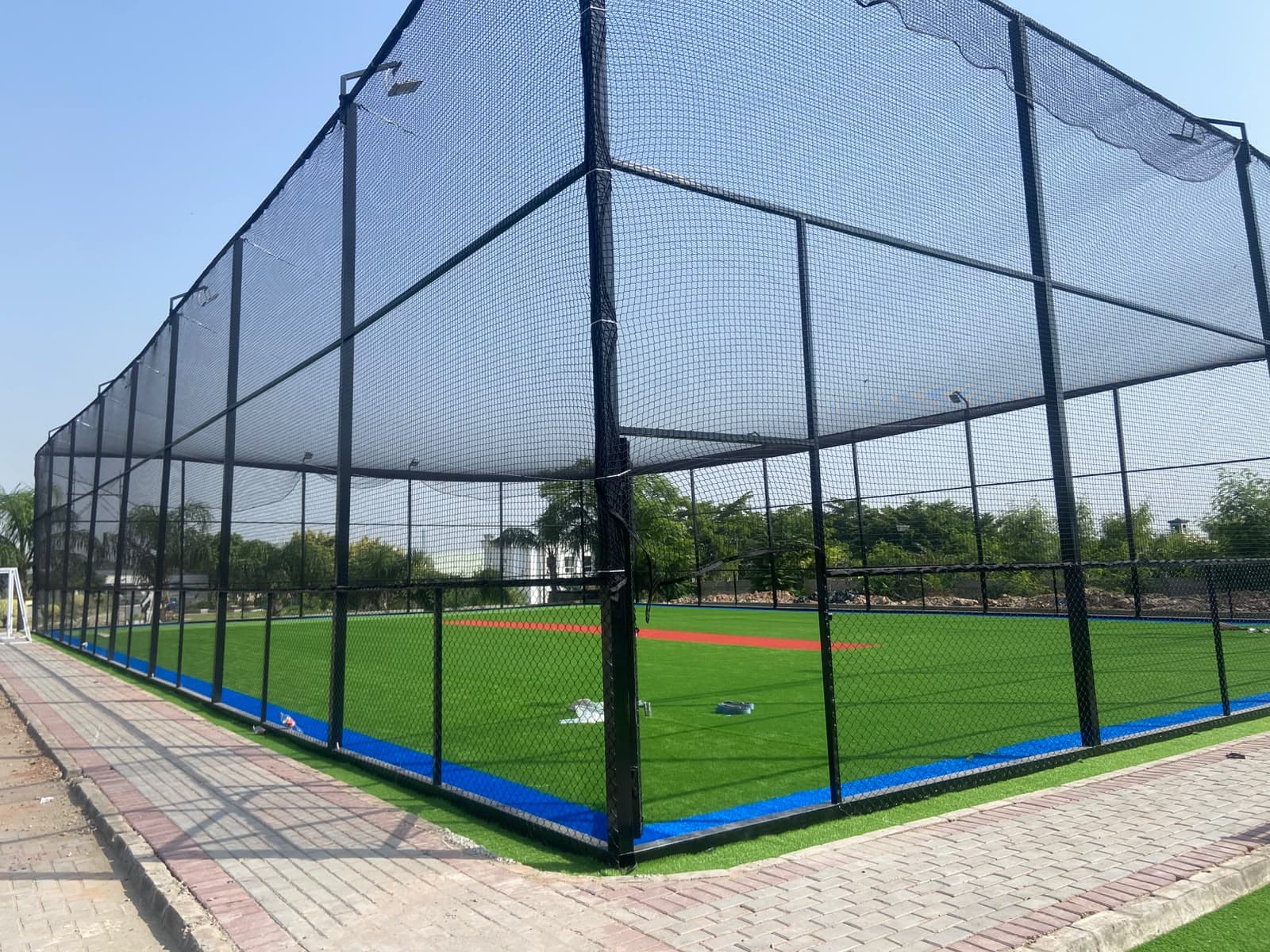 Wide overview of synthetic grass turf pitch, boundary netting cage, and floodlight masts at Football Ground Askari 14