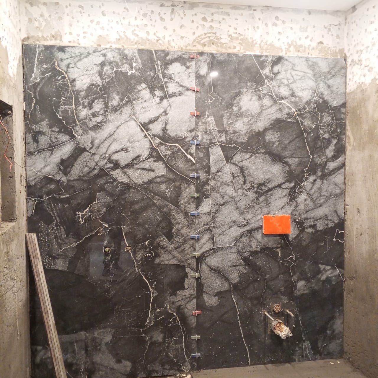 Bookmatched black marble porcelain slabs installed on a luxury bathroom feature wall with concealed plumbing cutouts in F-6 / F-7 Islamabad