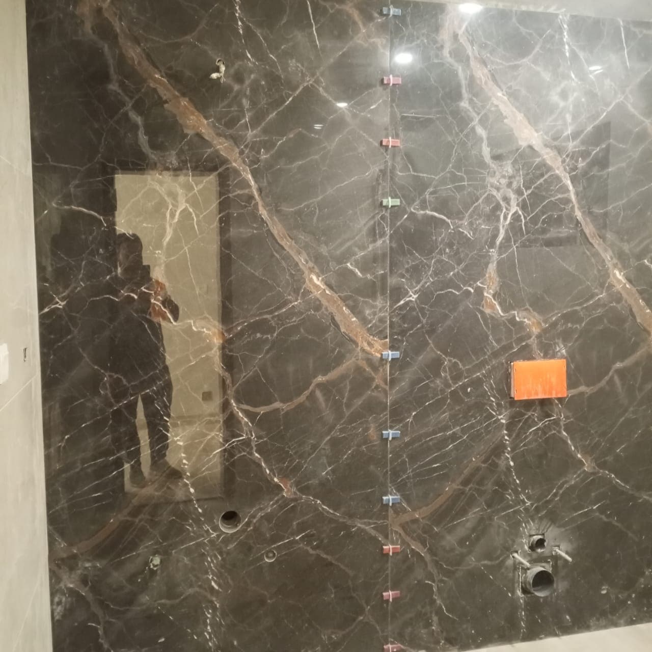Precision joint alignment on dark vein-matched bookmatch marble porcelain slabs for a master bathroom feature wall in F-6 / F-7 Islamabad