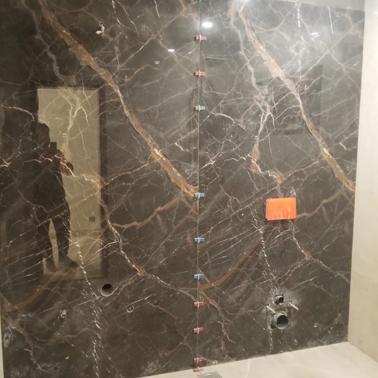 Dark Saint Laurent style marble porcelain slab feature wall with levelling clips along central bookmatch seam in F-6 / F-7 Islamabad