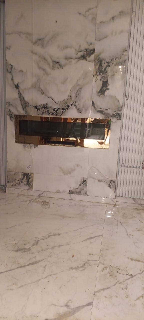 Polished porcelain marble floor reflecting the brass fireplace surround and marble slab feature wall in F-6 / F-7 Islamabad