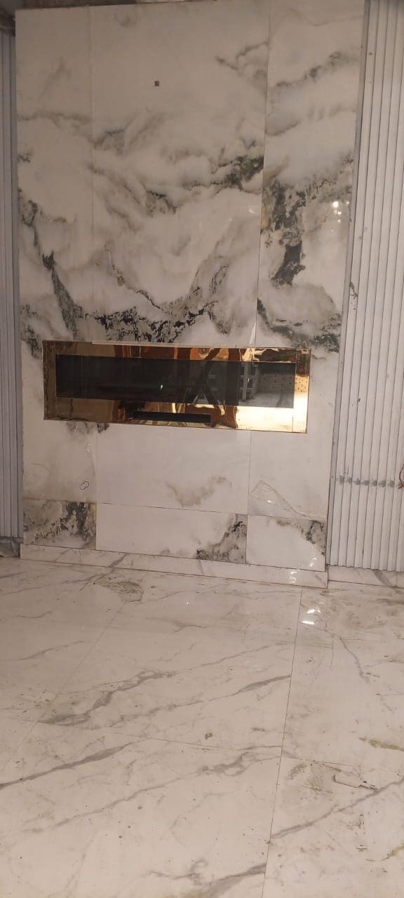 Dramatic marble porcelain slab fireplace feature wall with polished brass inset fireplace and fluted acoustic wall panels in F-6 / F-7 Islamabad