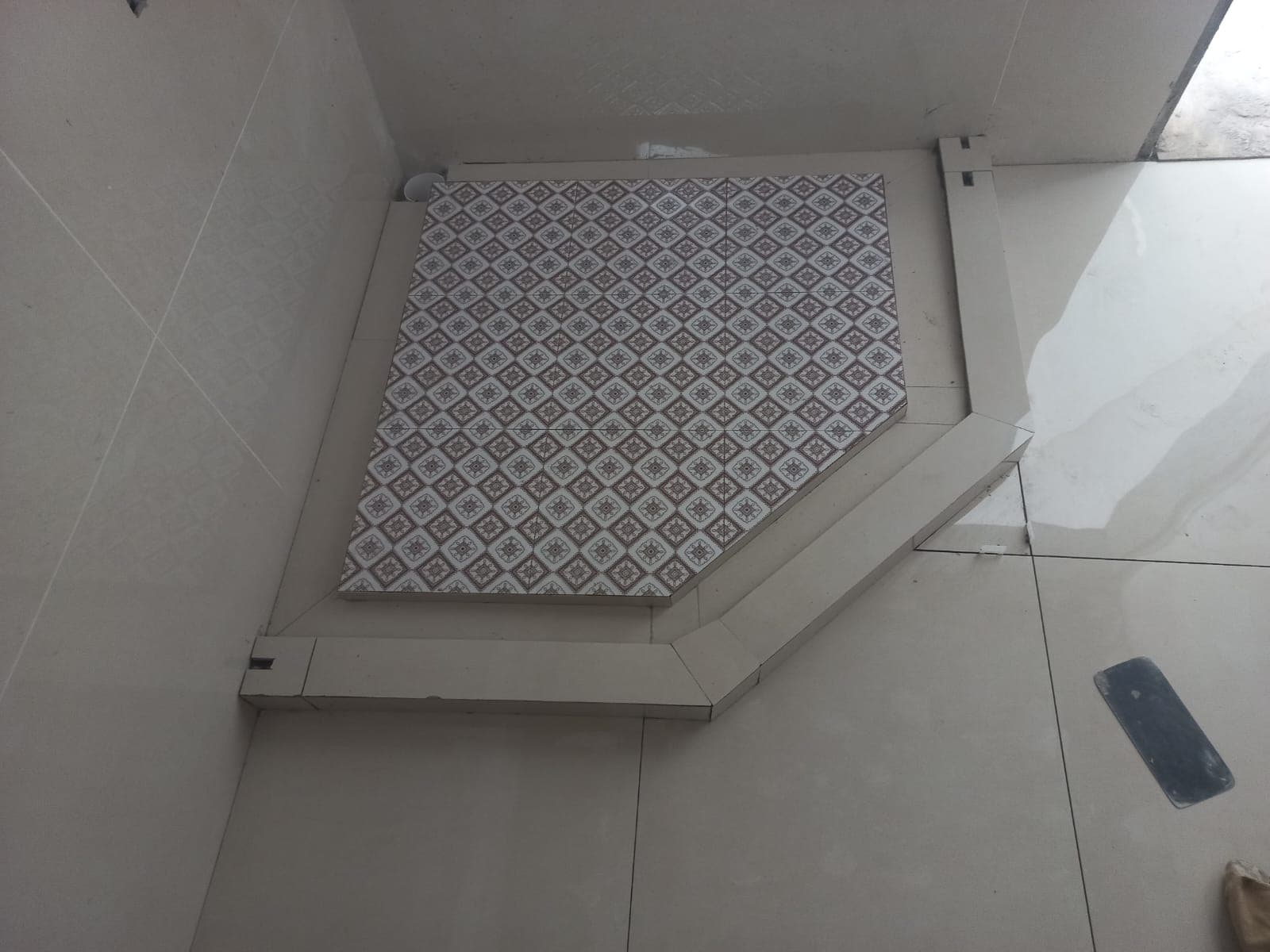 Pentagonal corner shower tray base with geometric pattern mosaic tile insert and mitred curb in F-6 / F-7 Islamabad residence