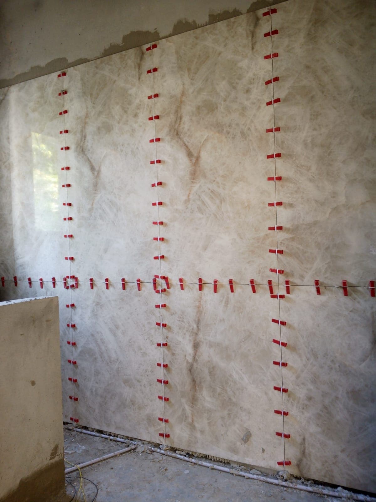 Full-height translucent onyx-look porcelain slab feature wall installation secured with precision levelling clips in F-6 / F-7 Islamabad
