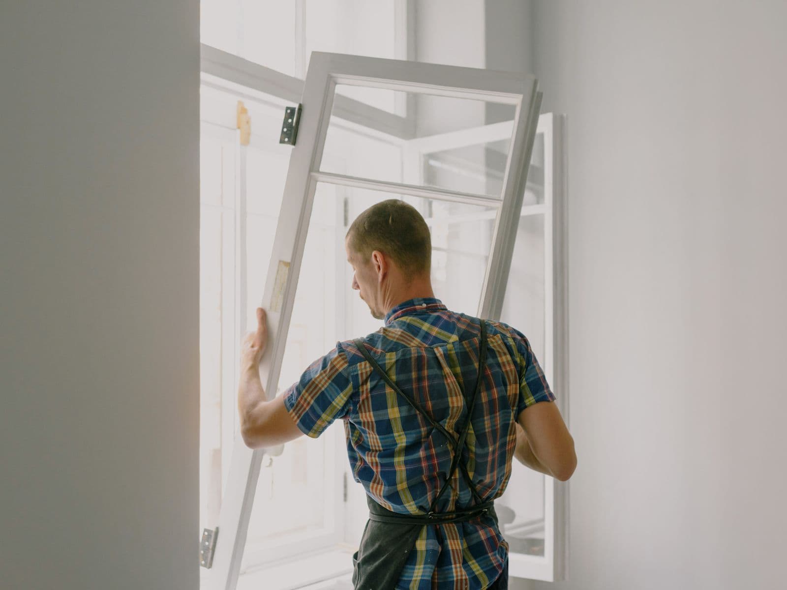 Installer fitting a new window frame in a bright interior