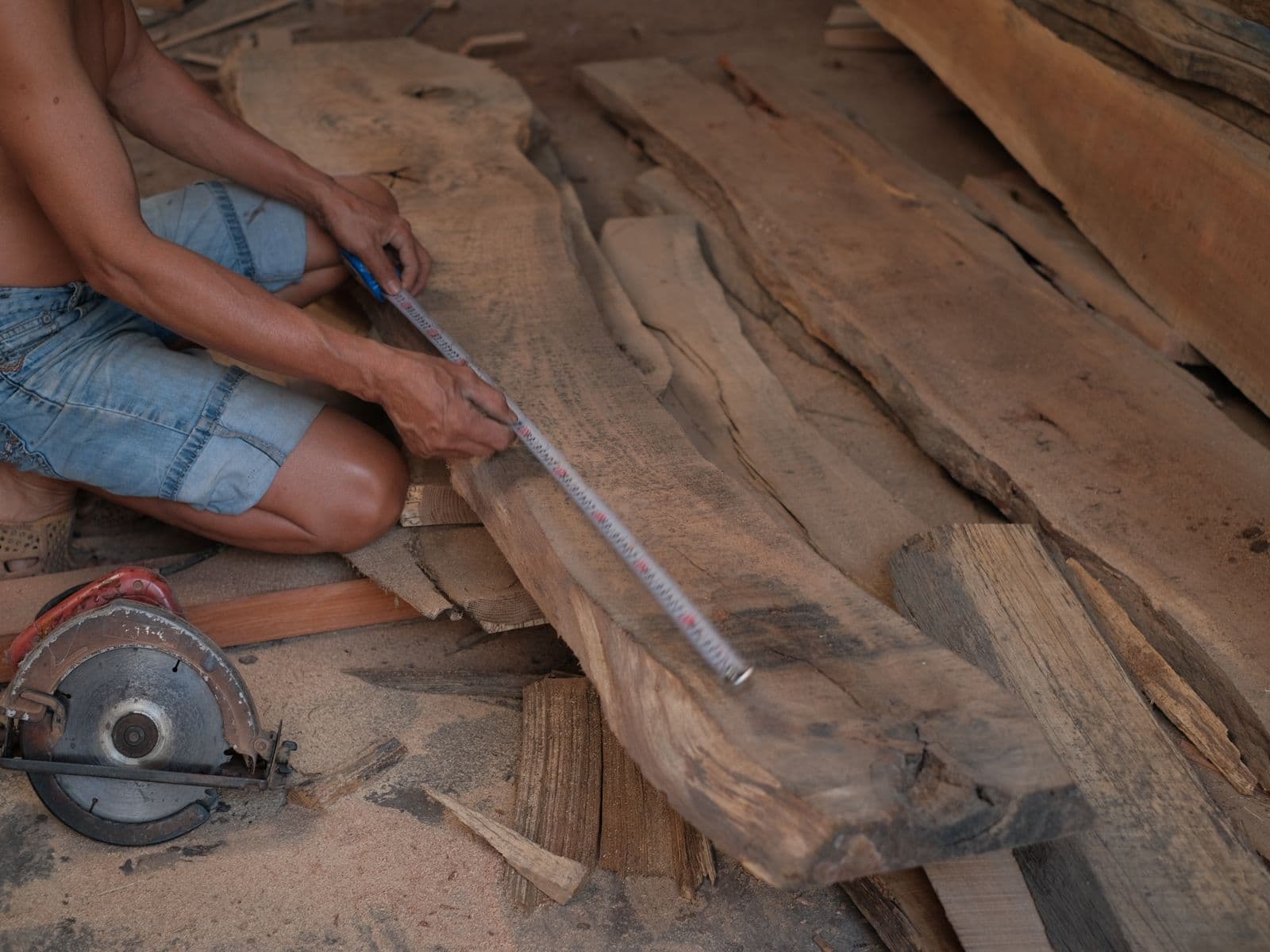 Carpenter measuring and marking a wooden plank before cutting