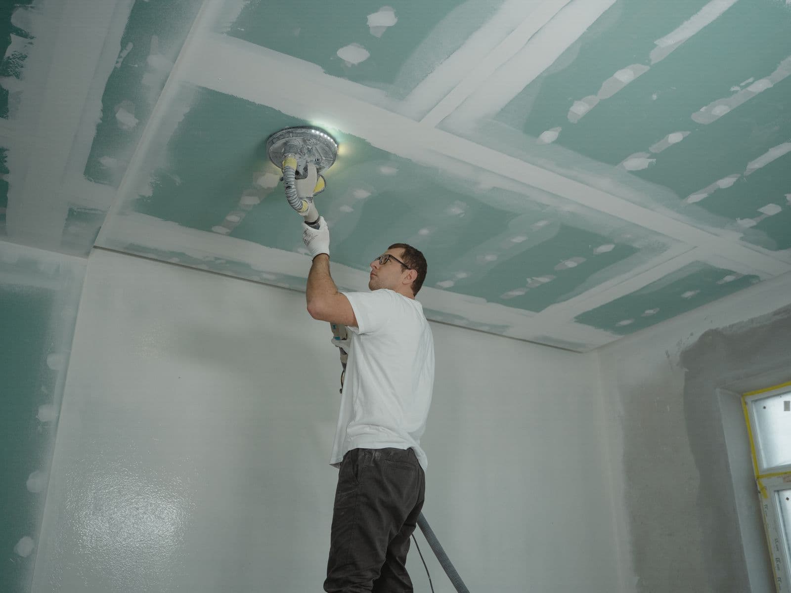 Worker smoothing and finishing an interior ceiling surface