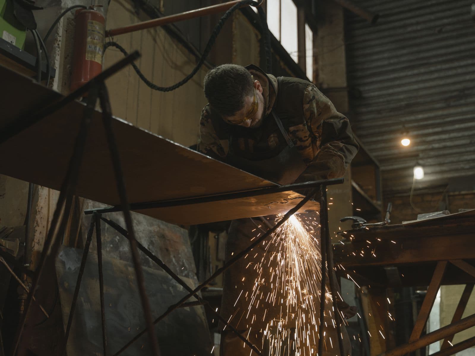 Welder joining a steel bar while wearing safety glasses