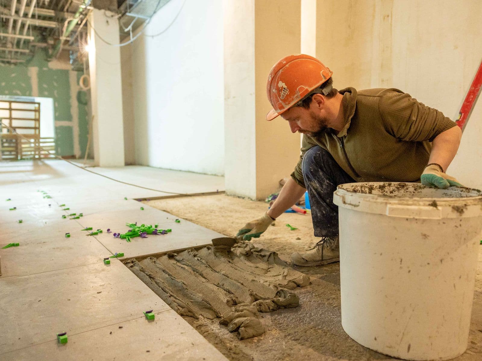 Construction worker bedding floor tiles during an interior renovation