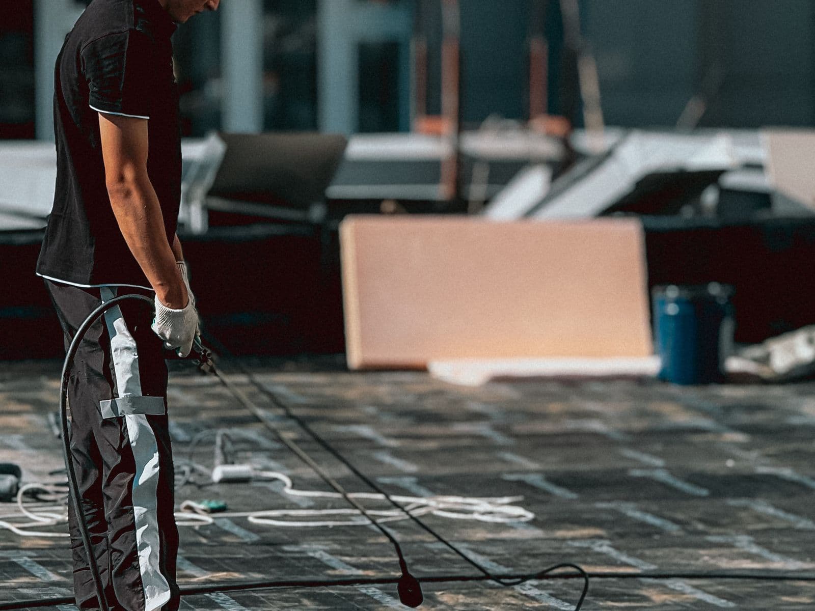 Worker roller-applying a waterproofing coat across a rooftop