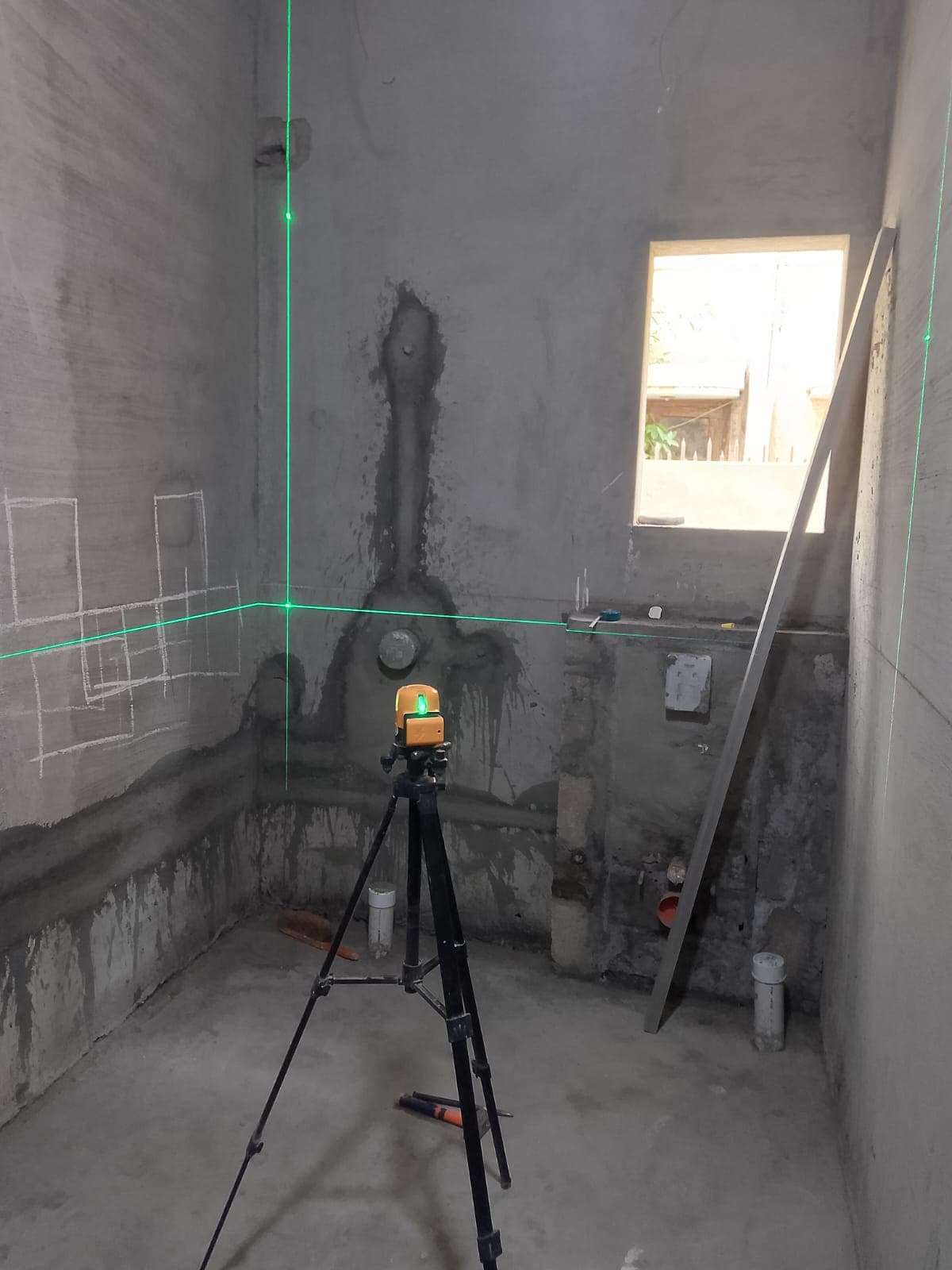 Raw concrete floor being checked with a 360-degree laser level before tiling