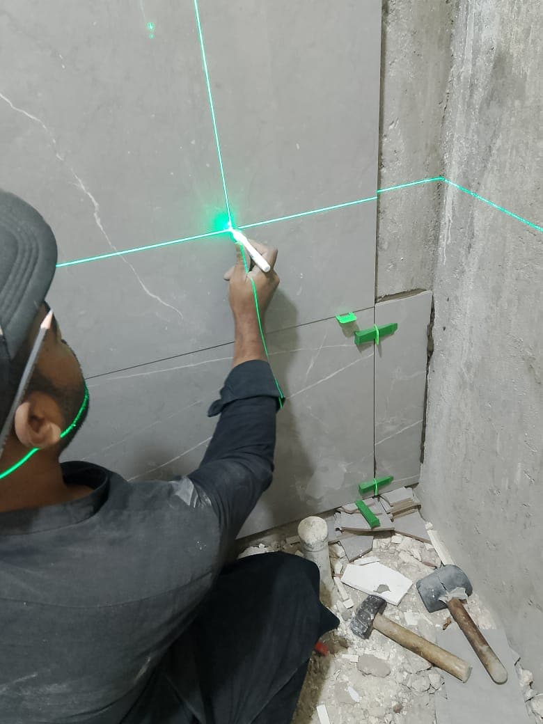 Technician marking a laser grid on a floor before tiling